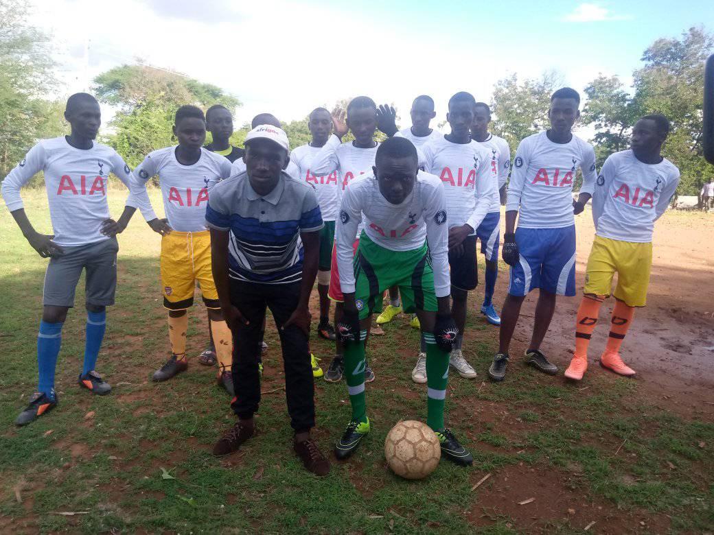 Placeholder photo: a Kenyan youth football team posing with their coach on a dirt pitch
